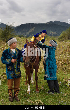 Sundet Toi Beschneidung mit jungen Pferd und Männer in traditionellen kasachischen Shapan Fell und Borik Hut Stockfoto