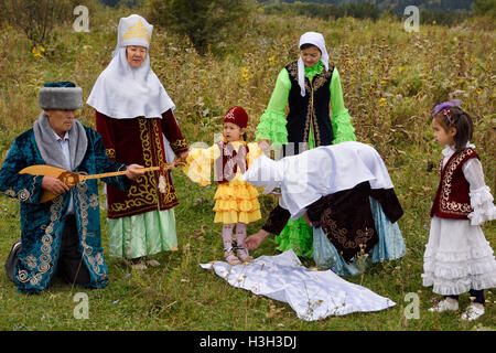 Tusau Kesu schneiden die Füße des Rope Binding Kind mit einer Schere den kasachischen traditionelle Zeremonie mit jungen Mädchen Kasachstan Stockfoto