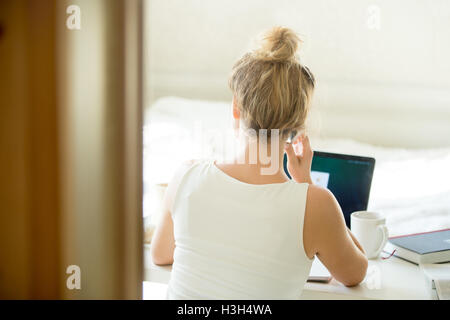 Frau sitzt hinten am Tisch am Telefon sprechen. Stockfoto