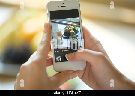 Hände halten eine Telefon mit Lebensmittel-Bild auf dem Bildschirm Stockfoto