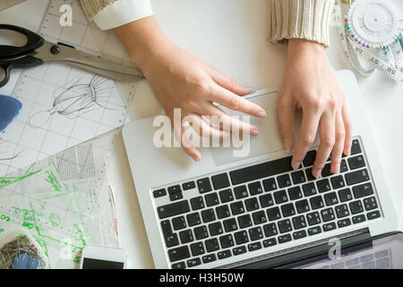 Hände arbeiten mit einem Laptop, Nähen Zubehör rund um Stockfoto