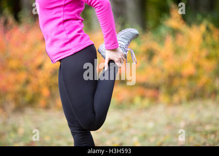 Aufwärmen im Freien im Herbst. Quadrizeps stehend Stockfoto