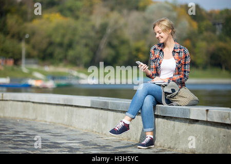 Porträt von eine junge attraktive Mädchen sitzen an der Brücke Stockfoto