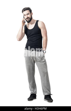 Young passen bärtigen Mann in Sportbekleidung Lächeln und reden über das Handy. Ganzkörper-Länge-Porträt isoliert auf weiss Stockfoto