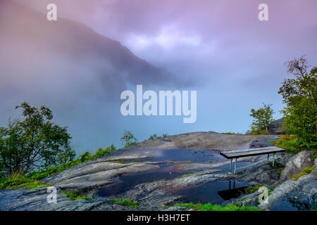 Berglandschaft in frühen Morgenstunden mit bewölktem Himmel. Zusammensetzung der Natur mit Sitzbank. Stockfoto
