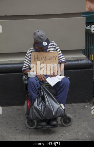 Mann im Rollstuhl bittet auf dem Bürgersteig am Broadway im Stadtteil SOHO in der Innenstadt von Manhattan, NYC. Stockfoto