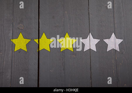 Vier gelbe Ranking Sterne auf schwarzem Hintergrund aus Holz Stockfoto