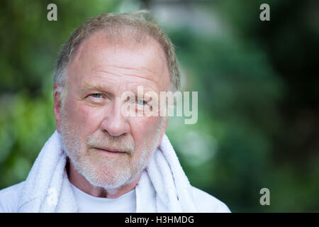 Closeup Kopfschuss Porträt von glücklich, selbstbewusst, fröhlich, lächelnden senior reifer Mann, isolierten grüne Bäume Laub Hintergrund Stockfoto