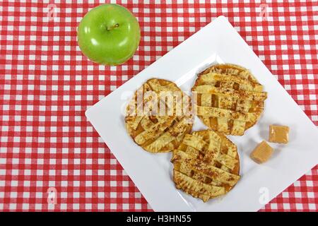 Apfelkuchen Kekse mit Karamell Bonbons auf weiße quadratische Platte mit grünem Apfel Stockfoto