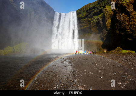 Touristen und doppelter Regenbogen am Skogafoss Wasserfall in Island Stockfoto