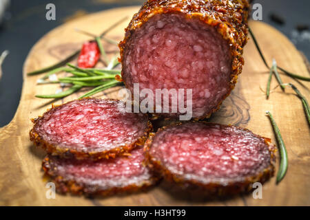 getrocknete Salami verkrustet in gemahlener roter Pfeffer auf dunklem Hintergrund Stockfoto