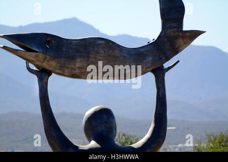 Close-up Statue eines Mannes, der einen Fisch in Richtung der Sonne Himmel in Wirikuta botanischen Garten Mexiko mit Bergen & blauer Himmel hält Stockfoto