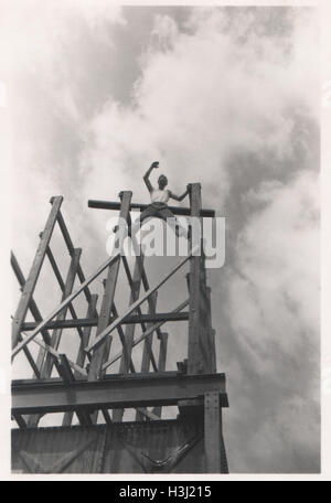 Bauarbeiter, der in einer prekären Position steht und auf einer Baustelle auf Trägern winkt. Das Foto wurde 10 im Base Ordnance Depot Royal Army Ordnance Corps (RAOC) im Gebiet Genefa Ismailia in der Nähe des Suezkanals 1952 aufgenommen. Stockfoto