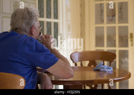 Cardiff, Wales. 14. März 2016. Eine ältere Frau sitzt am Küchentisch allein aus einem Becher zu trinken. © AimeeHerd Freelance Stockfoto