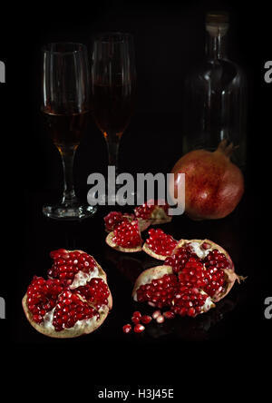 Segmente der Granatapfel und die ganze Frucht auf schwarzem Hintergrund Stockfoto