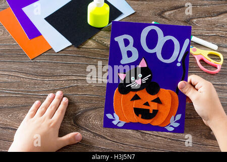 Das Kind erstellen eine Geburtstagskarte für Halloween Papier schwarze Katze Kürbis. Kleber, Schere, Blätter samt Papier auf einem Holztisch Stockfoto