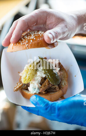 kernigen Burger Bun gehoben von der Burger zu verschiedenen Toppings wie Gurken, offenbaren Burger in einer weißen Essbrett statt Stockfoto