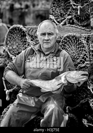 Anmerkung der Redaktion: Bild umgewandelt, BLACK AND WHITE Fischer Neil Messenger, Besitzer der Seahaze traditionelle Fischhändler in Brighton, East Sussex, hält einen frisch gefangenen Kabeljau, wie er seinen Fang in Brighton Marina landet, wie nationale Meeresfrüchte Woche bis zum 14. Oktober weiter. Stockfoto