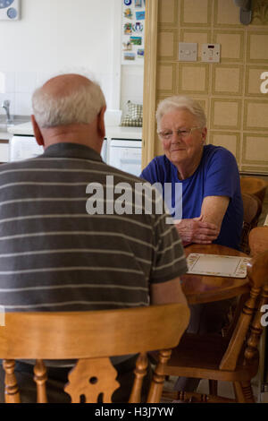 Holmes Chapel, England. 14. März 2016. Ein älteres Ehepaar sitzt an einem hölzernen Küchentisch. © AimeeHerd Freelance Stockfoto