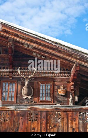 Detail der traditionellen hölzernen Schweizer Haus im Winter, mit einigen Dekoration wie eine ausgestopfte Rentiere Kopf. Stockfoto