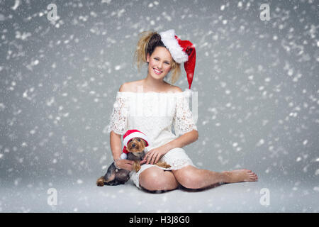 Schöne Mädchen mit Hund Yorkie in Santa cap Stockfoto