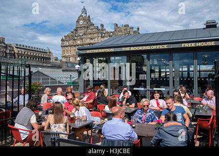 Kunden genießen einen Drink im Gasthaus auf Waverley Bridge, Edinburgh mit dem Balmoral Hotel im Hintergrund. Stockfoto