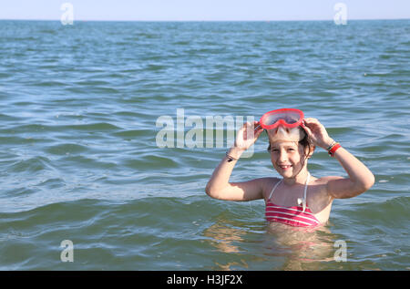 schönes kleines Kind Lächeln während des Spiels mit der Tauchmaske im Meer Stockfoto