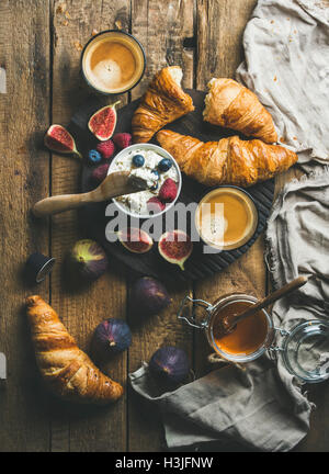 Frühstück mit Croissants, hausgemachte Ricotta-Käse, Feigen, frische Beeren, Honig und Espresso-Kaffee auf dunklen Gläser servieren Bo Stockfoto