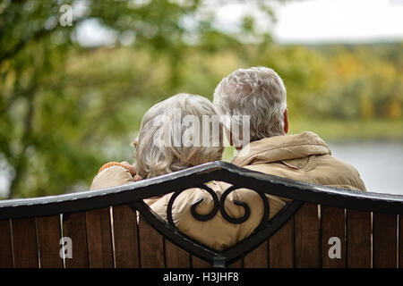 Älteres Ehepaar sitzt auf einer Bank im Herbst park Stockfoto