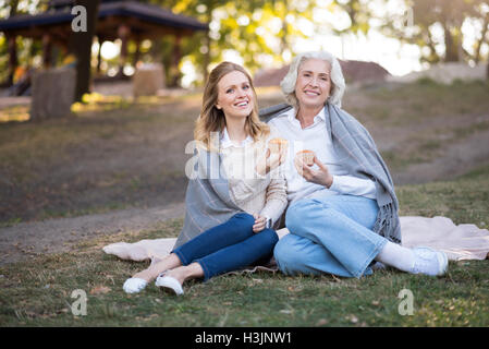 Zwei glückliche amüsiert Frauen sitzen auf dem Boden Stockfoto