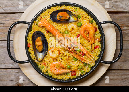 Spanische Paella auf einer hölzernen Matte auf einem Holztisch Stockfoto