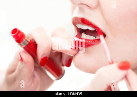 Jemand Auftragen von Lippenstift auf die Lippen der jungen Frau Stockfoto