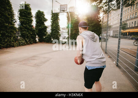 Rückansicht Schuss eines Streetball Spieler Basketball zu spielen. Junger Kerl spielen Basketball auf Freiplatz. Stockfoto