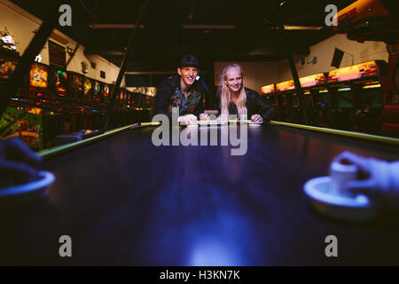 Junge Freunde, Air-Hockey zu spielen, im Freizeitpark. Mann und Frau, die ein Spiel von Air-Hockey im Spielzimmer. Stockfoto