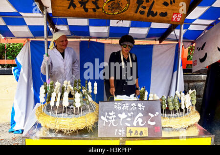 Reisenden thai-Frau testen, Kochen und Fotografieren mit Kreditor Dango japanische Snack auf Straßenevent Markt der Fushimi Inari-taisha Stockfoto