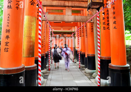 Japanische Leute und Reisende Ausländer zu Fuß reisen und besuchen Sie auf Pfad im Inneren durch einen Tunnel aus Torii-Tore bei Fushimi-Ina Stockfoto