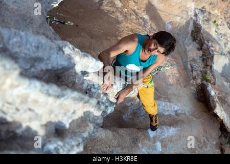 Ältere männliche Extremkletterer, die ungewöhnlich geformten Felsen hängen Stockfoto