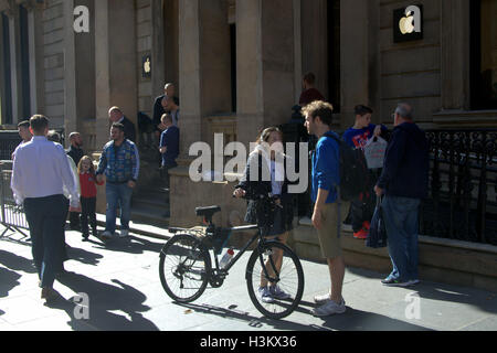 Apple speichern Glasgow Straßenszene ein Junge ein Mädchen und ein Fahrrad Stockfoto