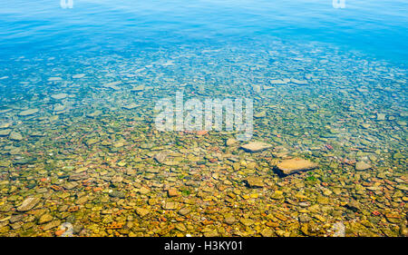 Transparente Flachwasser mit felsigen Boden, verblassen, tieferes Wasser oben. Stockfoto