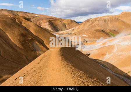 Rote und braune Hügel mit Schnee und Dampf- und zwei Touristen in Kerlingarfjoll auf Island. Stockfoto