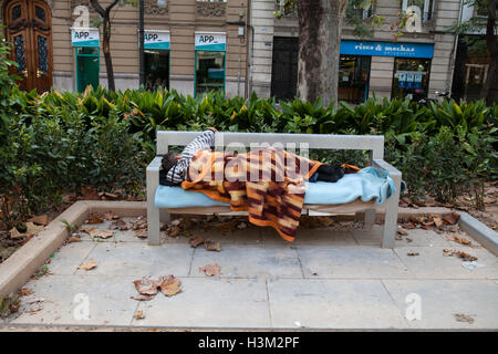 Obdachloser schlafen auf einer Bank in Valencia Stockfoto