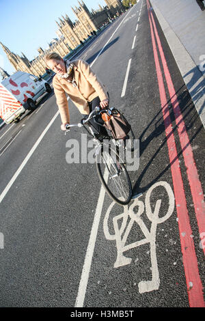 Radfahrer fährt entlang Radwegs auf Westminster Bridge, mit Houses of Parlament/Big Ben im Hintergrund. Sonnigen Morgen in Oc Stockfoto