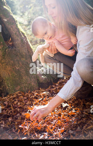 Mutter und Tochter hockend untersuchen lässt auf Waldboden Stockfoto