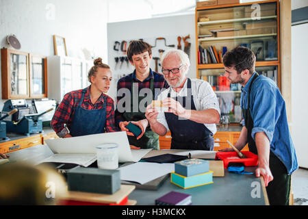 Senior männlichen Workshopleiter zeigen Materialien, junge Gruppe von Männern und Frauen im Buch-Kunst-workshop Stockfoto