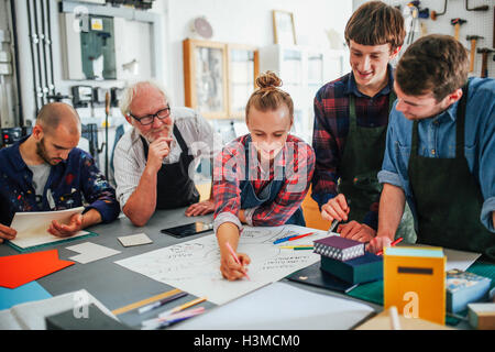 Ältere männliche Handwerker brainstorming Ideen mit Gruppe von jungen Männern und Frauen im Buch-Kunst-workshop Stockfoto