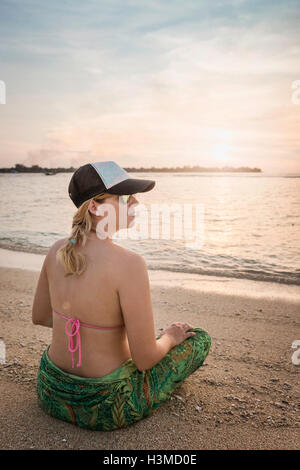 Junge Frau Schneidersitz sitzen am Strand, Gili Meno, Lombok, Indonesien Stockfoto