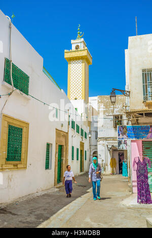 Medina-Wohnstraße mit gelben Minarett auf dem Hintergrund in Sfax. Stockfoto