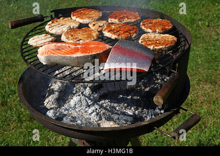 Huhn oder Truthahn Geflügel Fleisch Grill gegrillte Burger für Hamburger und Lachs Fisch Filetsteak zubereitet am Grill Rauch Grill o Stockfoto