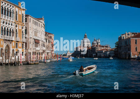 Ein Boot Segeln entlang des Canal Grande mit der Kirche "Madonna della Salute" im Hintergrund Stockfoto