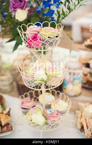 Ziemlich bunte Cupcakes auf eine Multi-tiered Kuchenplatte Stockfoto